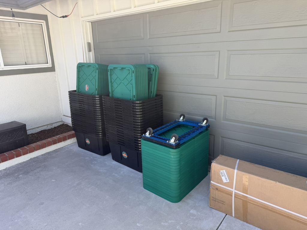 Stacks of clean 805 Totes moving totes, green lids, and dollies staged by the garage for delivery